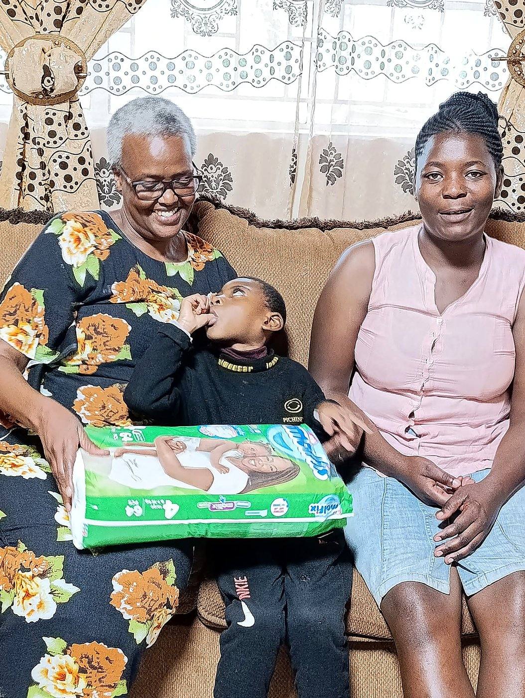 An elderly woman and a mother with a child receiving a gift