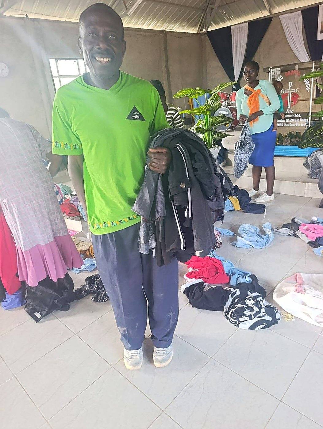 A volunteer smiling with a bundle of clothes he picked out at the drive